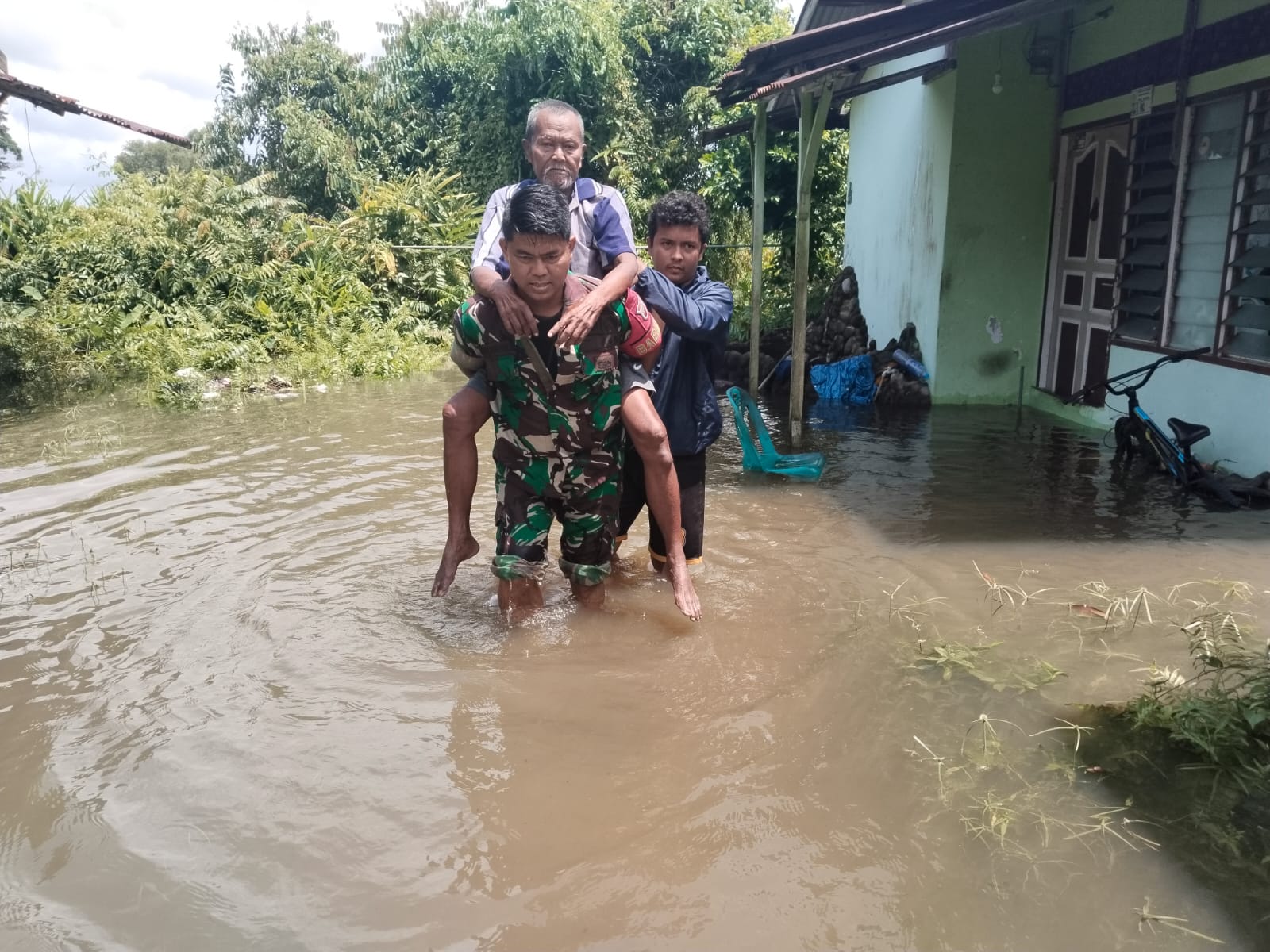 Babinsa Kelurahan Baran Barat, Koptu Billy Andra bantu mengevakuasi pria paruh baya yang terjebak dalam banjir dan menderita penyakit stroke.